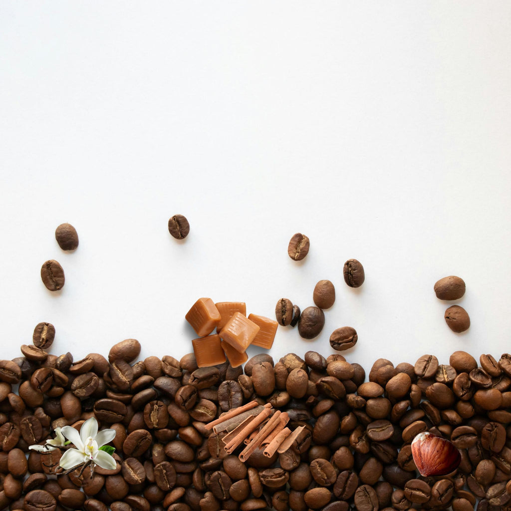 Coffee beans, caramel pieces, and a flower arranged on a white background