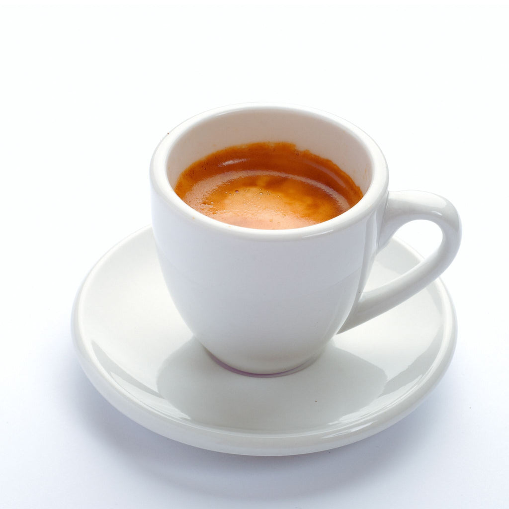 White espresso cup with a small amount of espresso on a white saucer